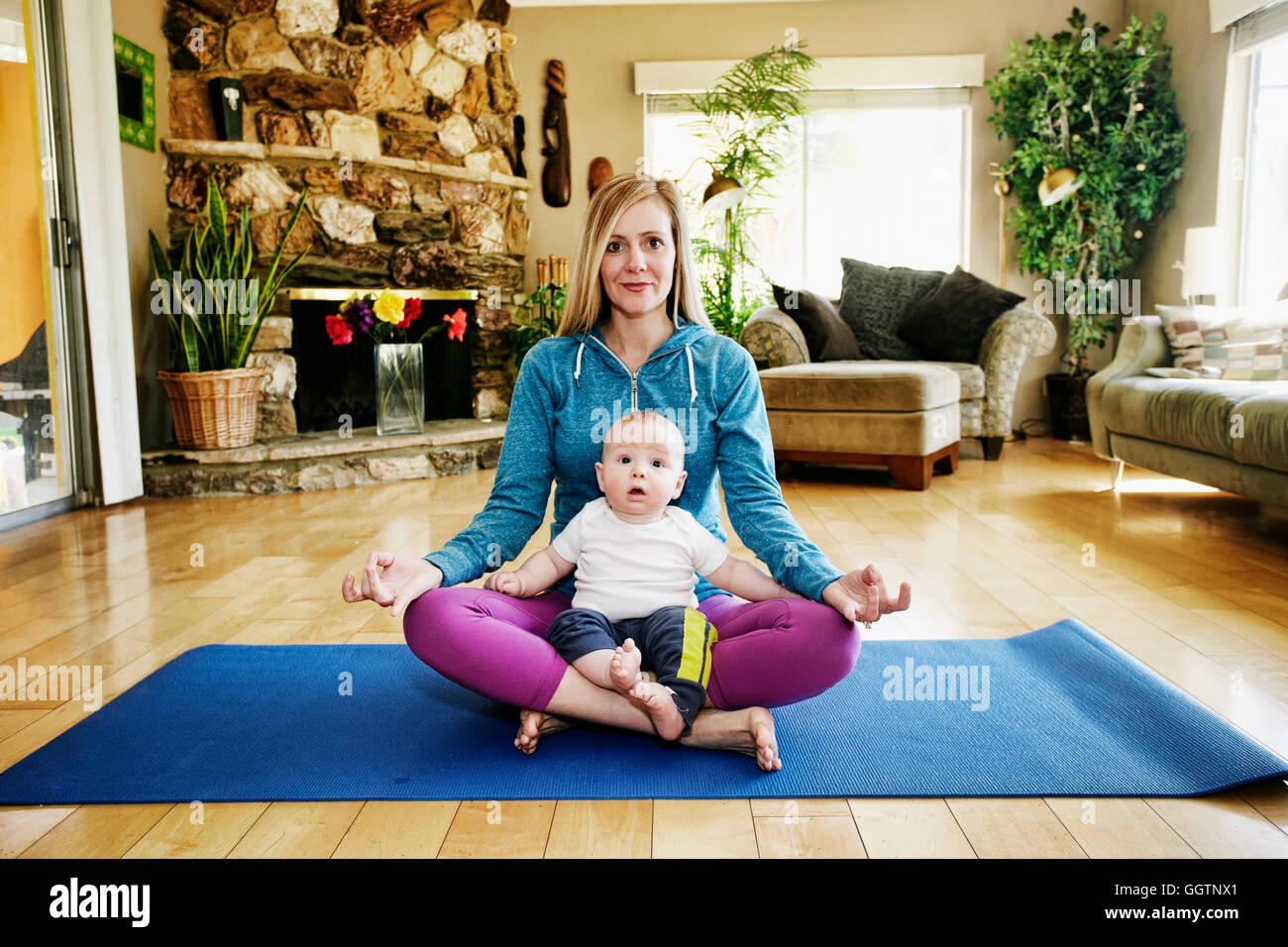 Mutter meditieren Gymnastikmatte mit Baby im Schoß Stockfoto