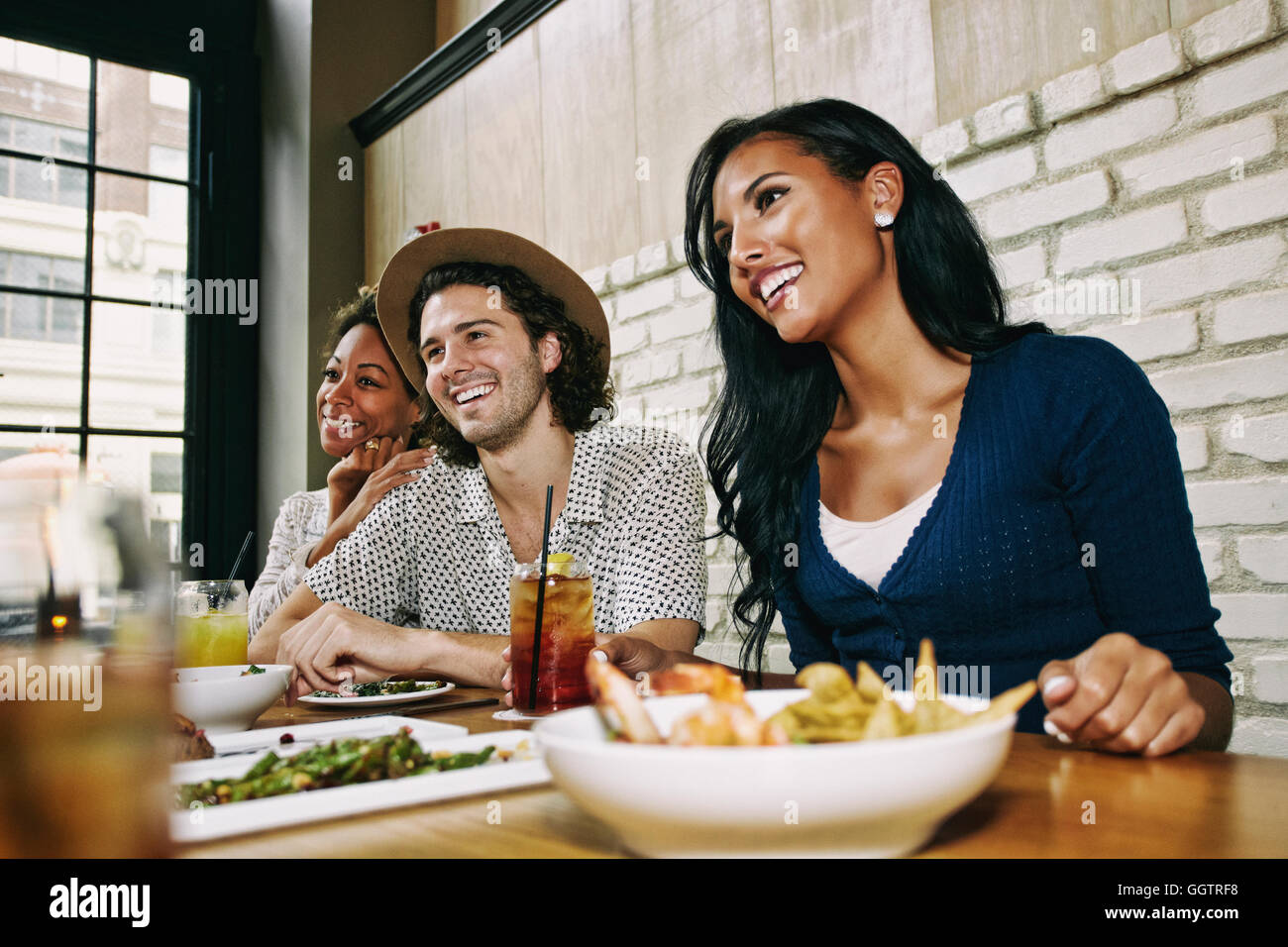 Lächelnd Freunde genießen Essen und Cocktails am Tisch in der Bar Stockfoto
