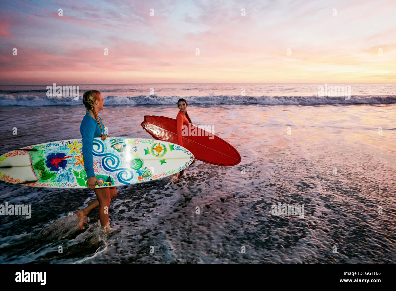Frauen, die Surfbretter in Ozeanwellen am Strand Stockfoto