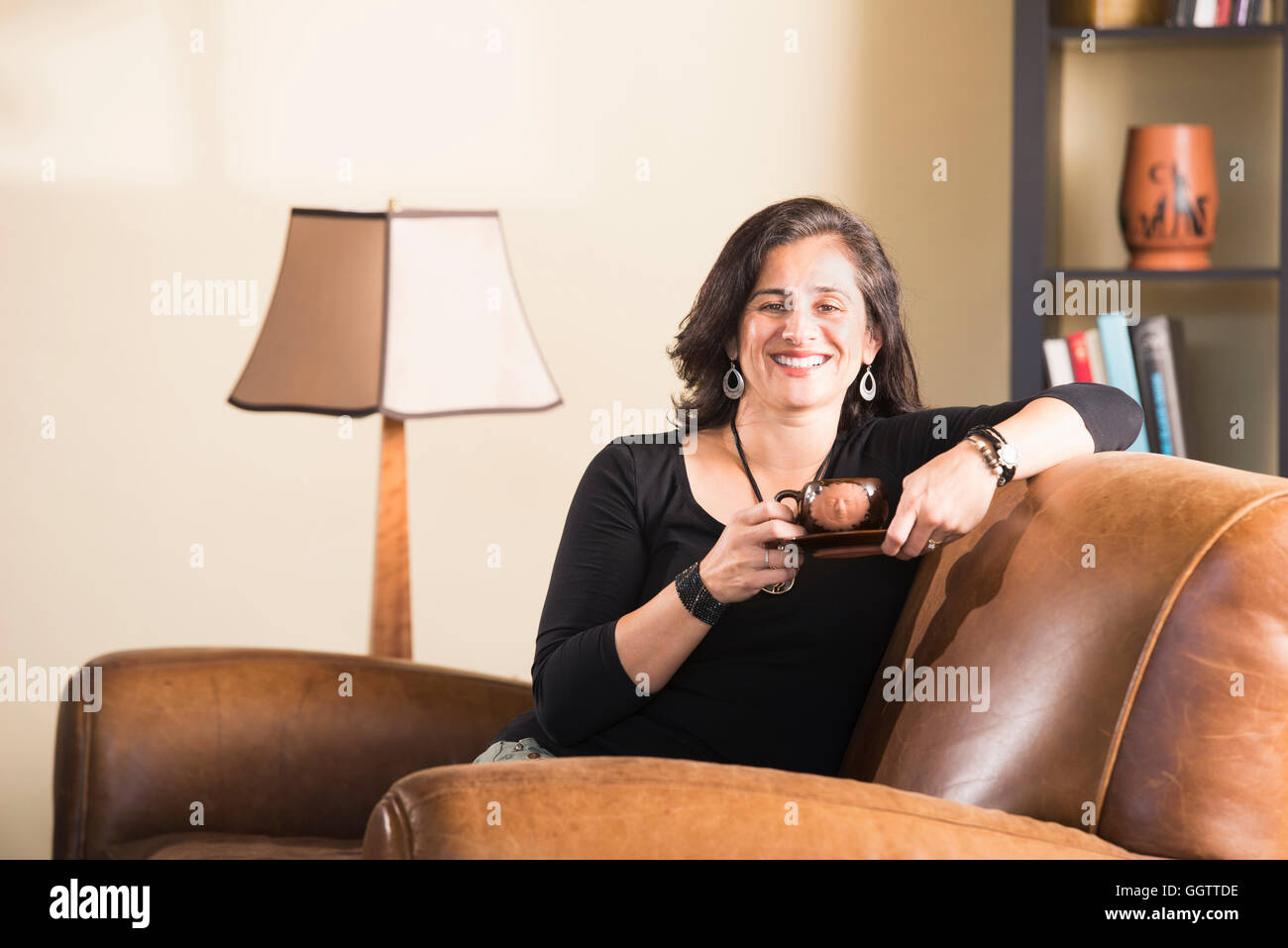 Hispanic Frau im Sessel, Kaffee trinken Stockfoto
