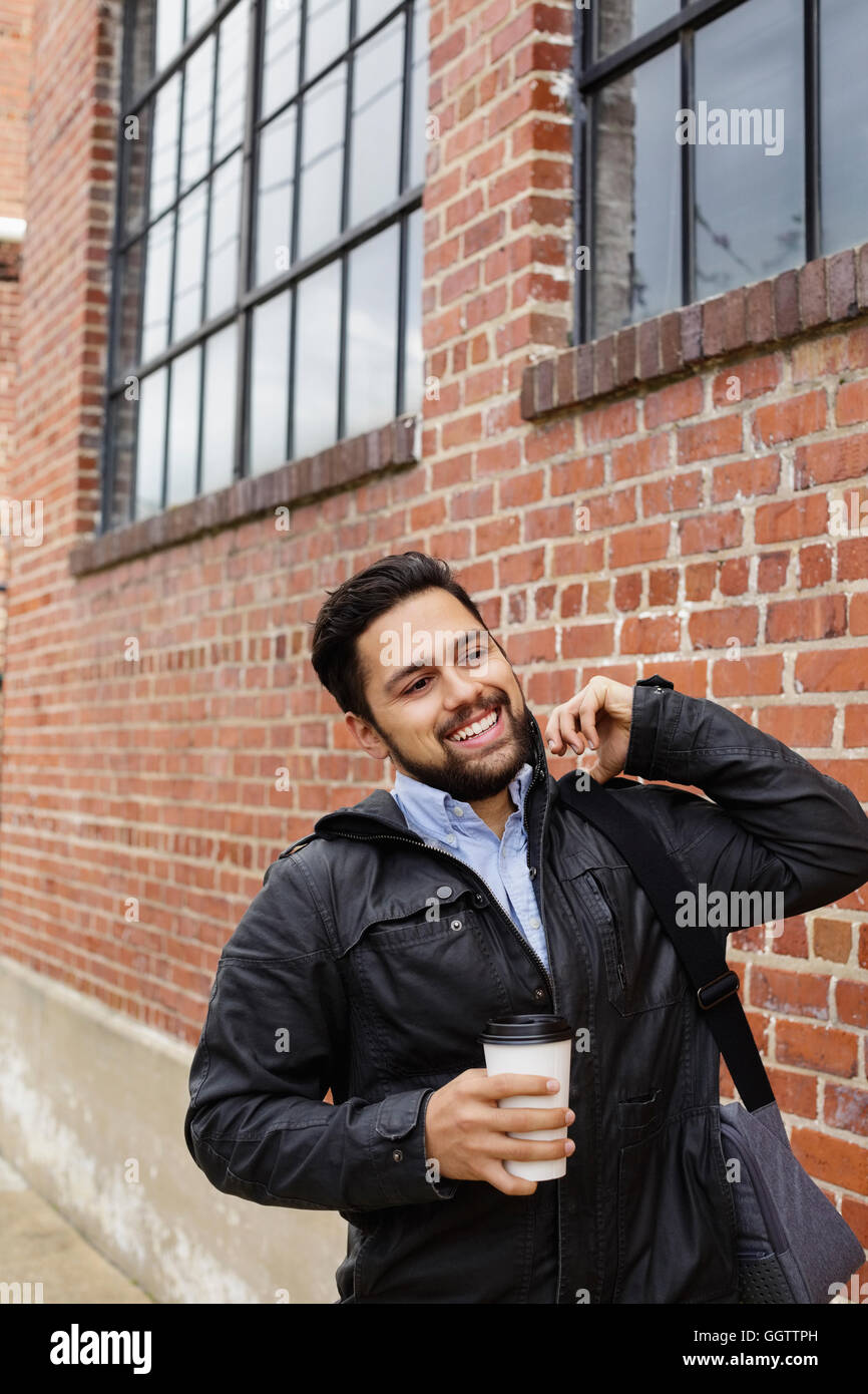 Hispanic Mann Tragetasche und Kaffeetasse in Stadt Stockfoto
