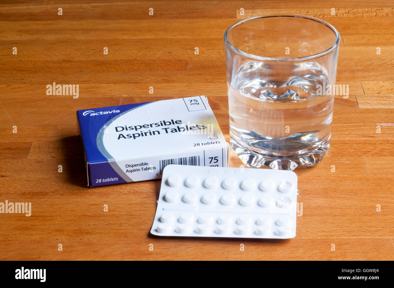 Ein Päckchen dispergierbar Aspirin mit einem Glas Wasser auf einem Nachttisch. Stockfoto