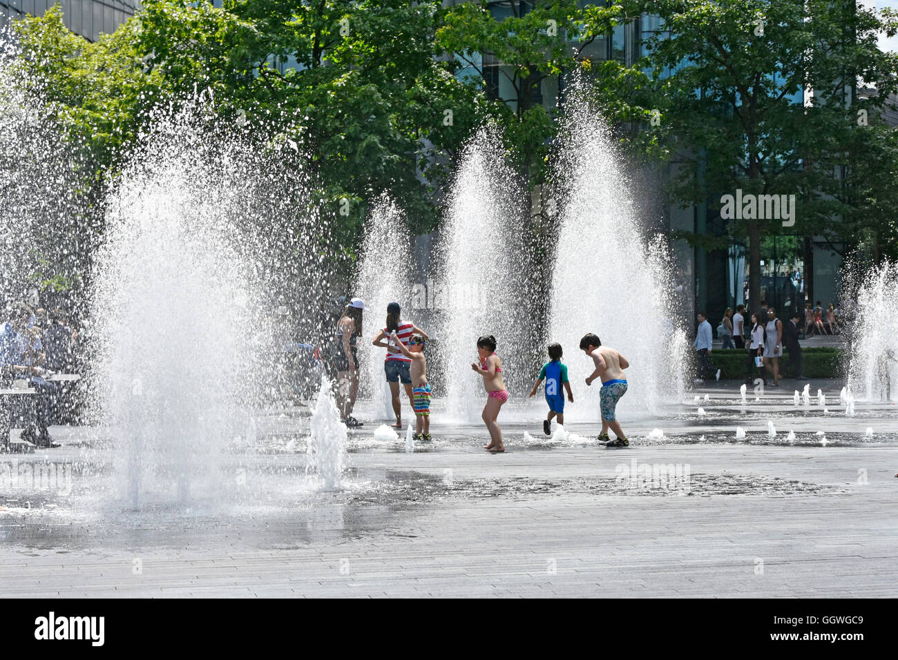 Kinder spielen in variabler Höhe Springbrunnen Jets nach dem Zufallsprinzip Timings im heißen Sommer Wetter ideal für Kinder im Freien London England Großbritannien Stockfoto