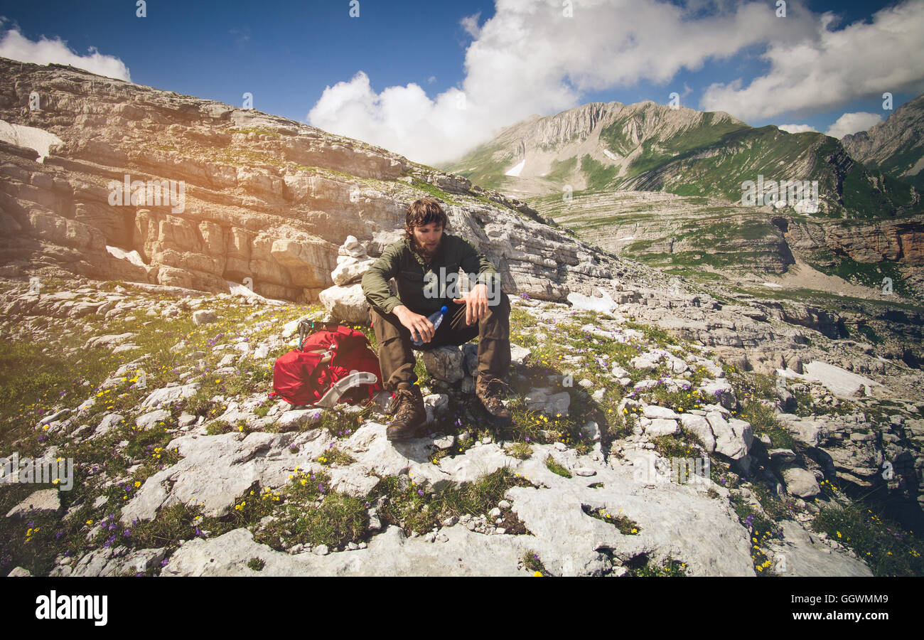 Reisender Mann mit Rucksack mit Flasche entspannende Reisen Lifestyle Konzept Berge im Hintergrund Sommer Urlaub Aktivität ou Stockfoto