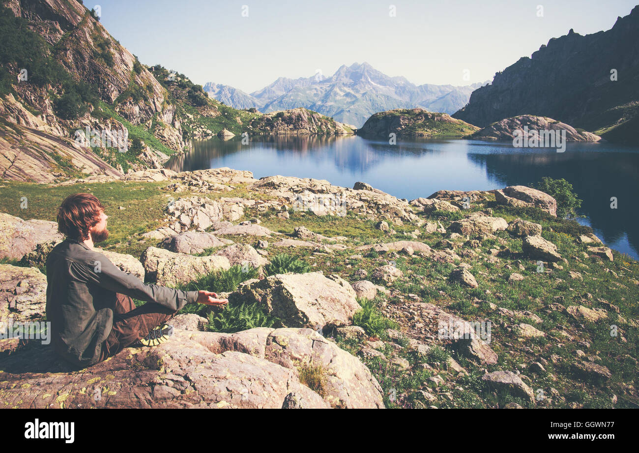 Reisender Mann entspannende Yoga Meditation allein Lotus Pose auf Stein sitzend Reisen, gesunden Lebensstil-Konzept-See und die Berge sere Stockfoto