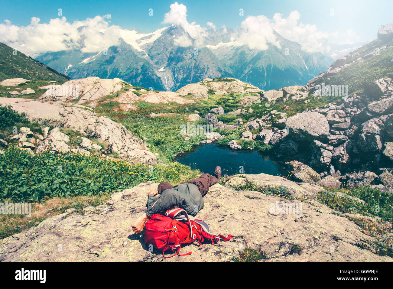 Mann, Verlegung, entspannender mit Rucksack auf Felsen Reisen Lifestyle Konzept heiteren Blick auf Berge Landschaft Sommerurlaub im freien Stockfoto