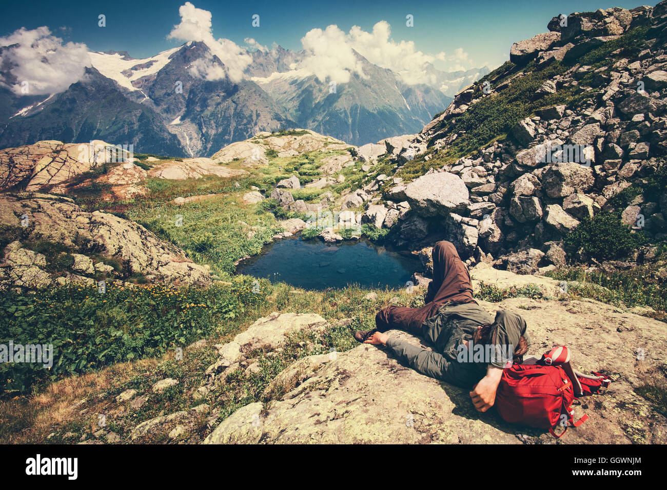Reisender Mann legen, entspannen mit Rucksack Reisen Lifestyle Konzept heiteren Blick Berge Landschaft auf Hintergrund Abenteuer Stockfoto