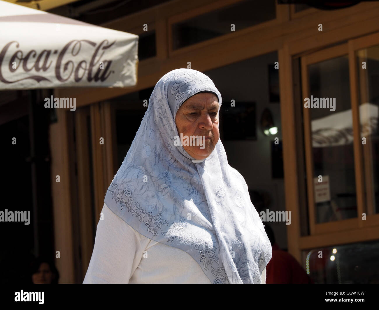 Frau in traditioneller muslimischer Tracht Wandern Basar von Sarajevo mit Coca-cola Schild im Hintergrund Stockfoto