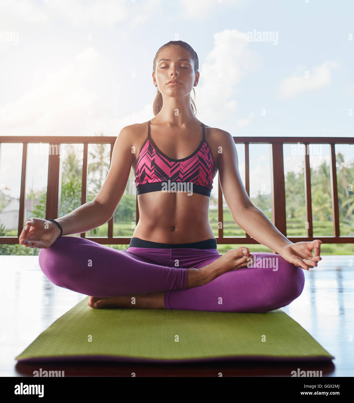 Junge Frau, die auf dem Boden sitzt, in Yoga-Pose mit Händen auf den Knien, Lotus-Pose. Fitness-weibliches Modell, das Yoga-Meditation macht. Stockfoto