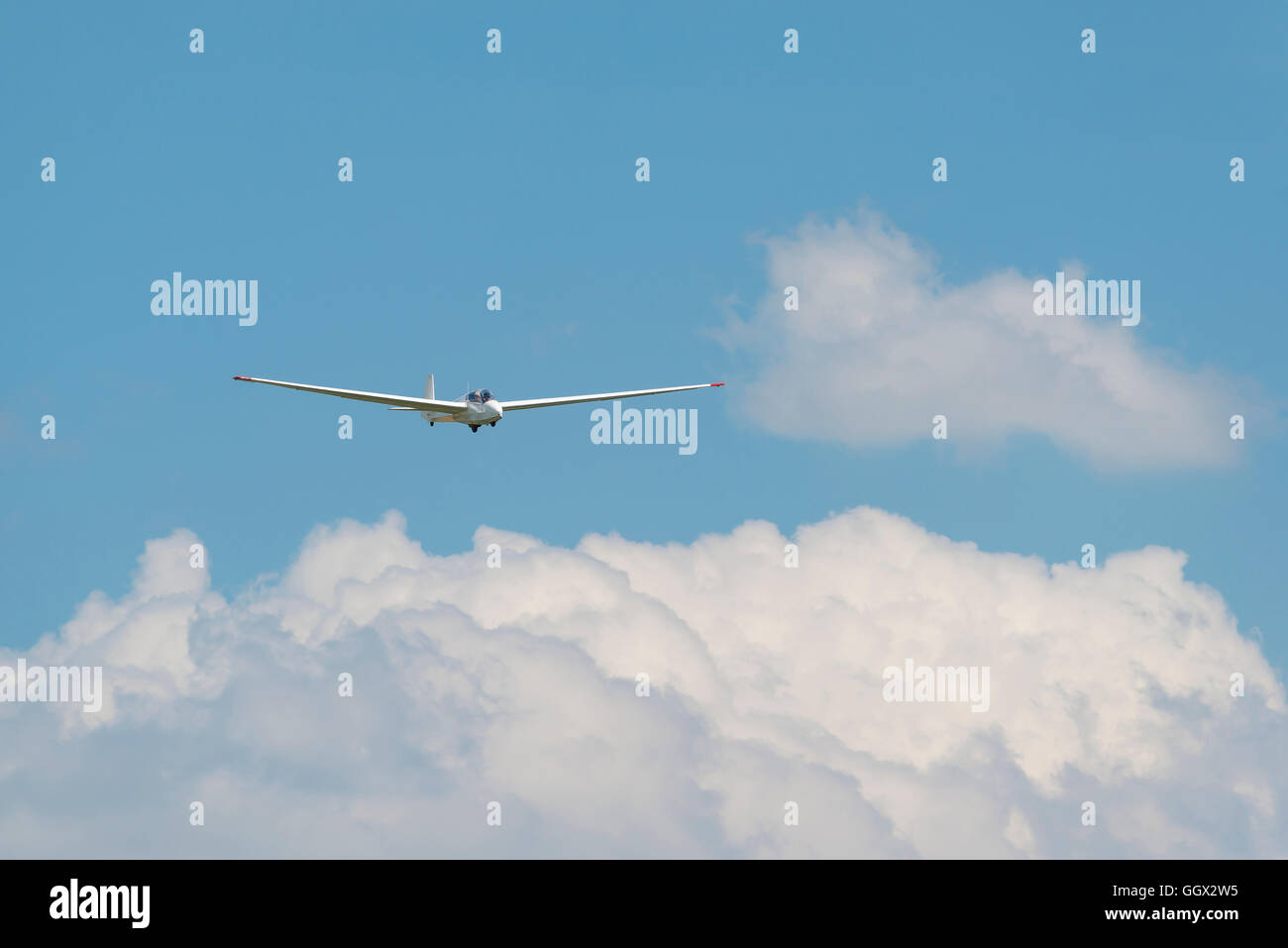 Segelflugzeug über weißen Wolken vor einem blauen Himmel als Hintergrundbild für Extremsportarten Stockfoto