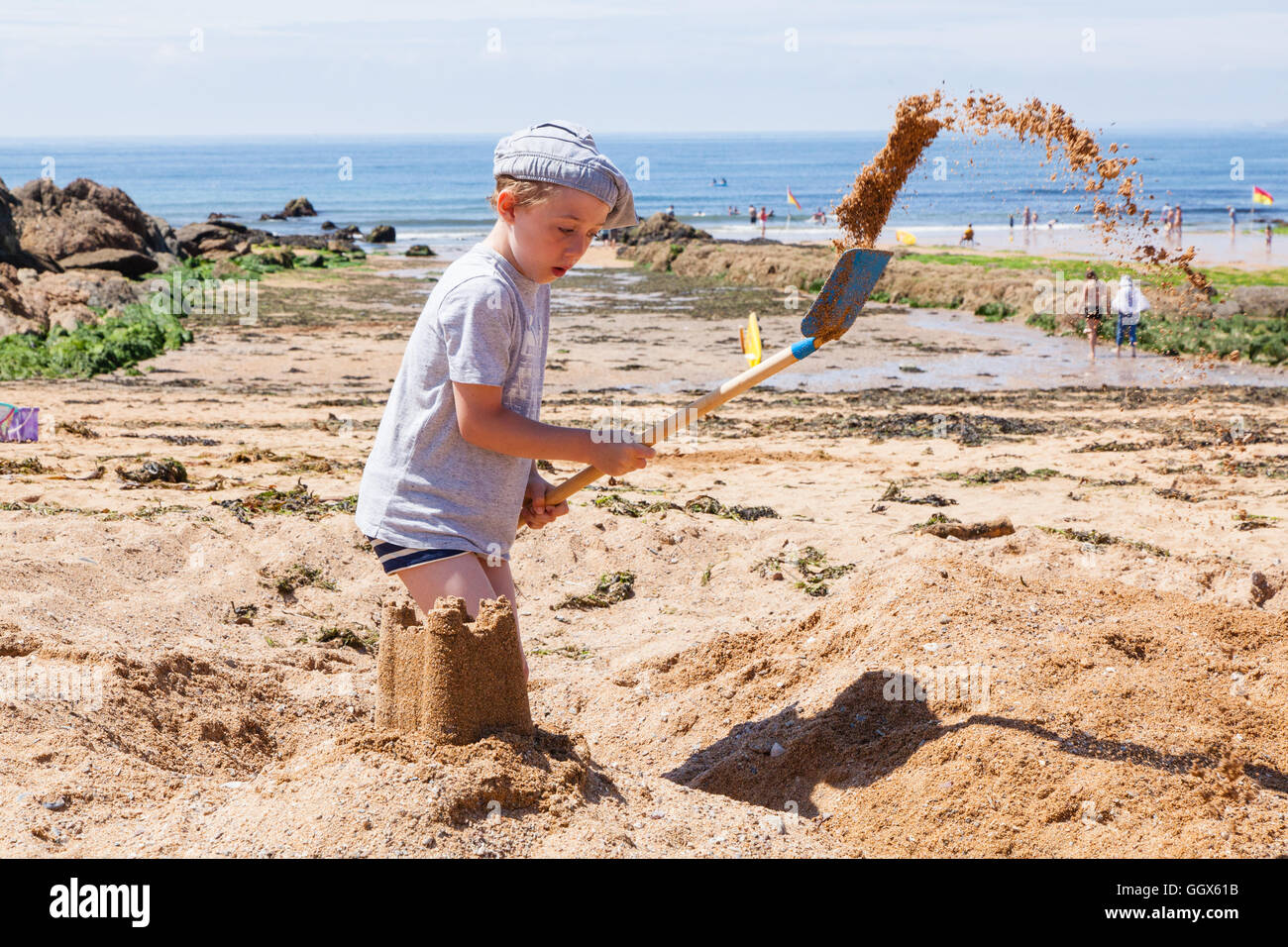 Sieben Jahre alten Jungen spielen im Sand am Strand von Mouthwell, Hope Cove, Devon, England, Vereinigtes Königreich. Stockfoto