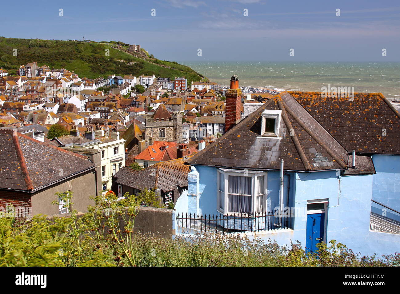 Gesamtansicht der Hastings Altstadt von West Hill, Hastings, Sussex, Großbritannien, grünen Hügeln und dem Meer im Hintergrund Stockfoto