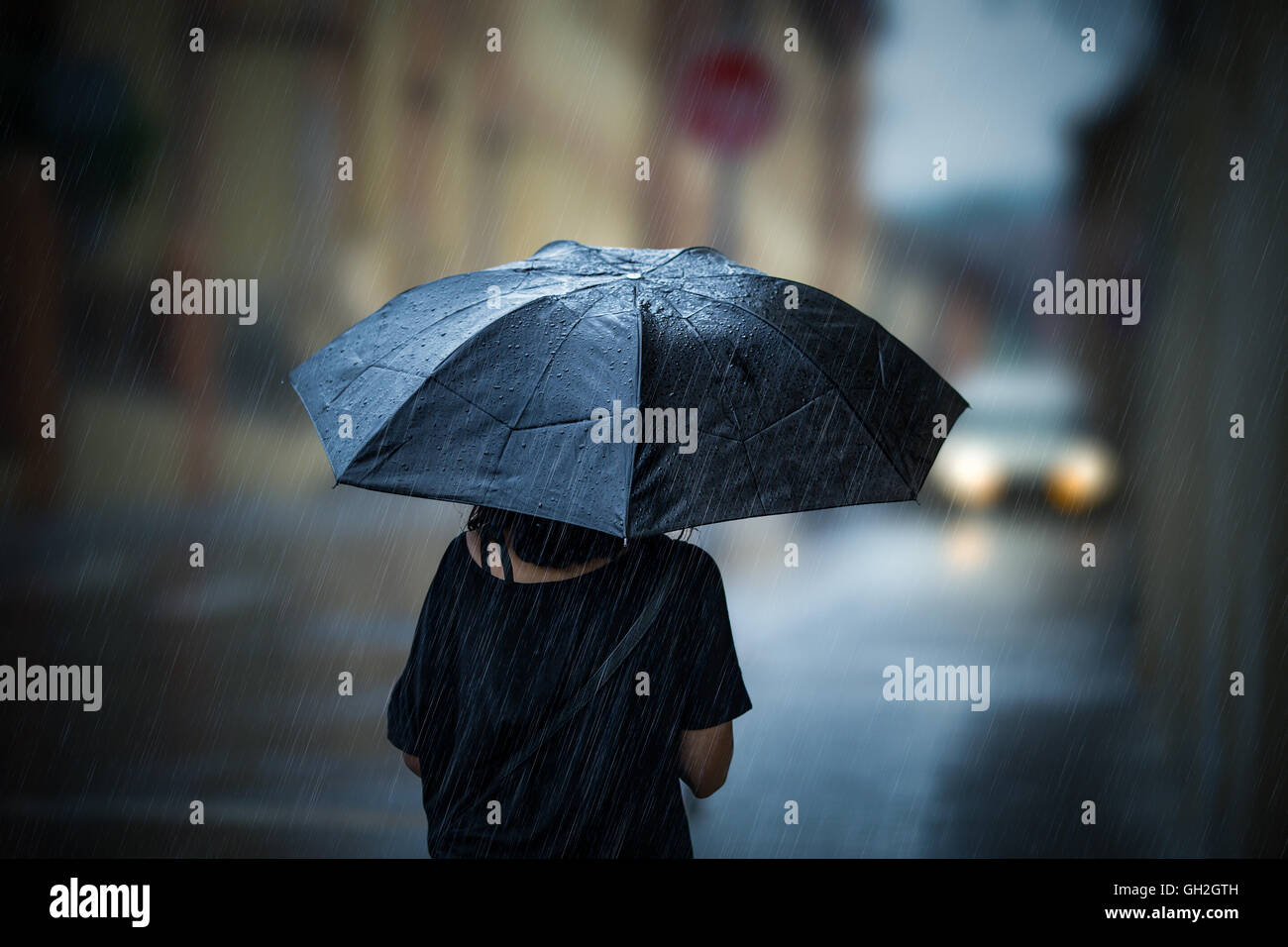 Mädchen mit Regenschirm an regnerischen Tag zu Fuß Stockfoto