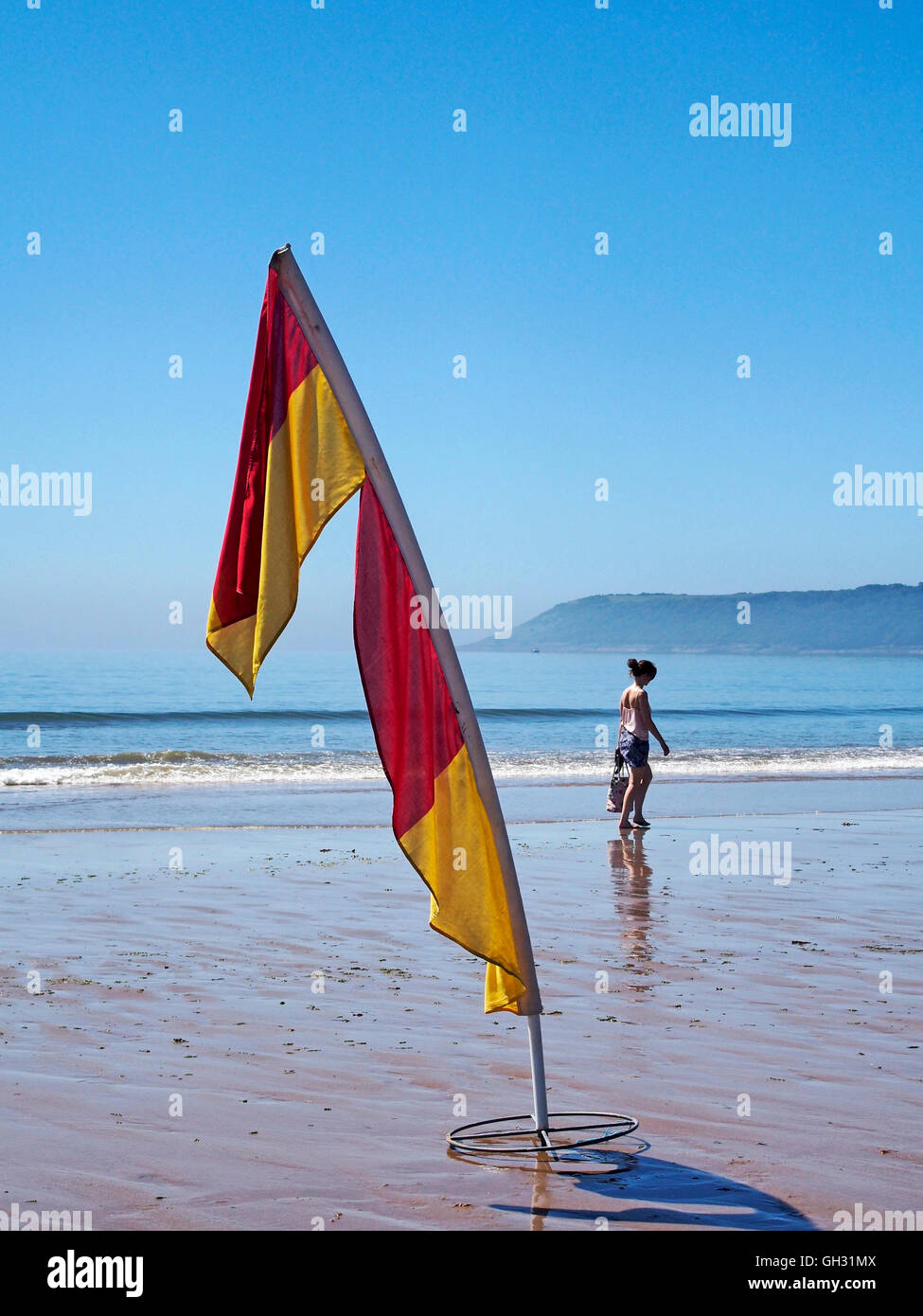 Rettungsschwimmer Markierungsfahnen zeigen patrouillierten gefährlich Strandbereich an drei Cliff Bay, Gower mit Menschen am Rand des Wassers. Stockfoto Rettungsschwimmer Markierungsfahnen zeigen patrouillierten gefährlich Strandbereich an drei Cliff Bay, Gower mit Menschen am Rand des Wassers. Stockfoto