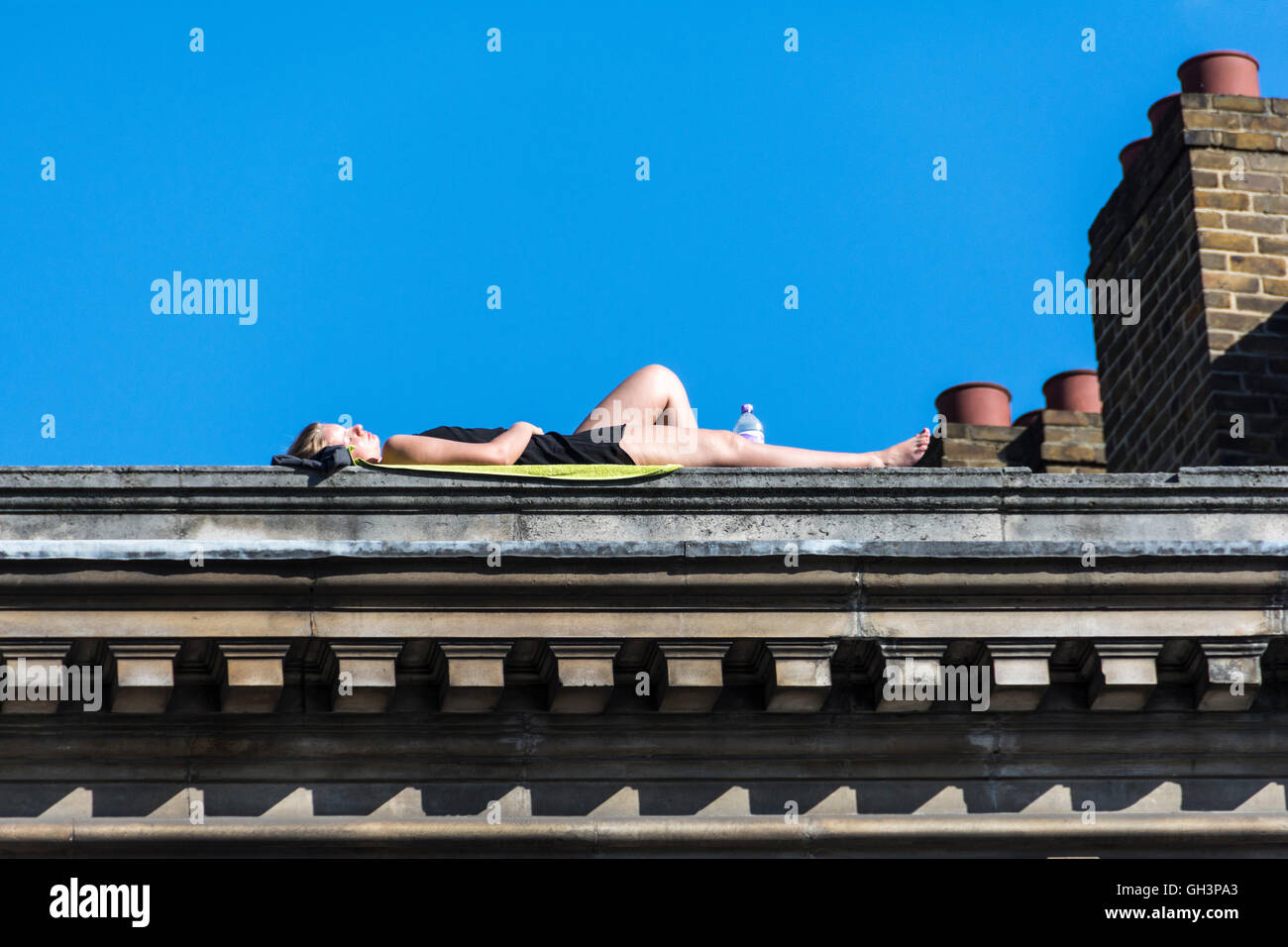 Eine Frau, die auf einem Dach in der Nähe des Borough Market in Southwark, London, England, liegt und sich sonnt Stockfoto