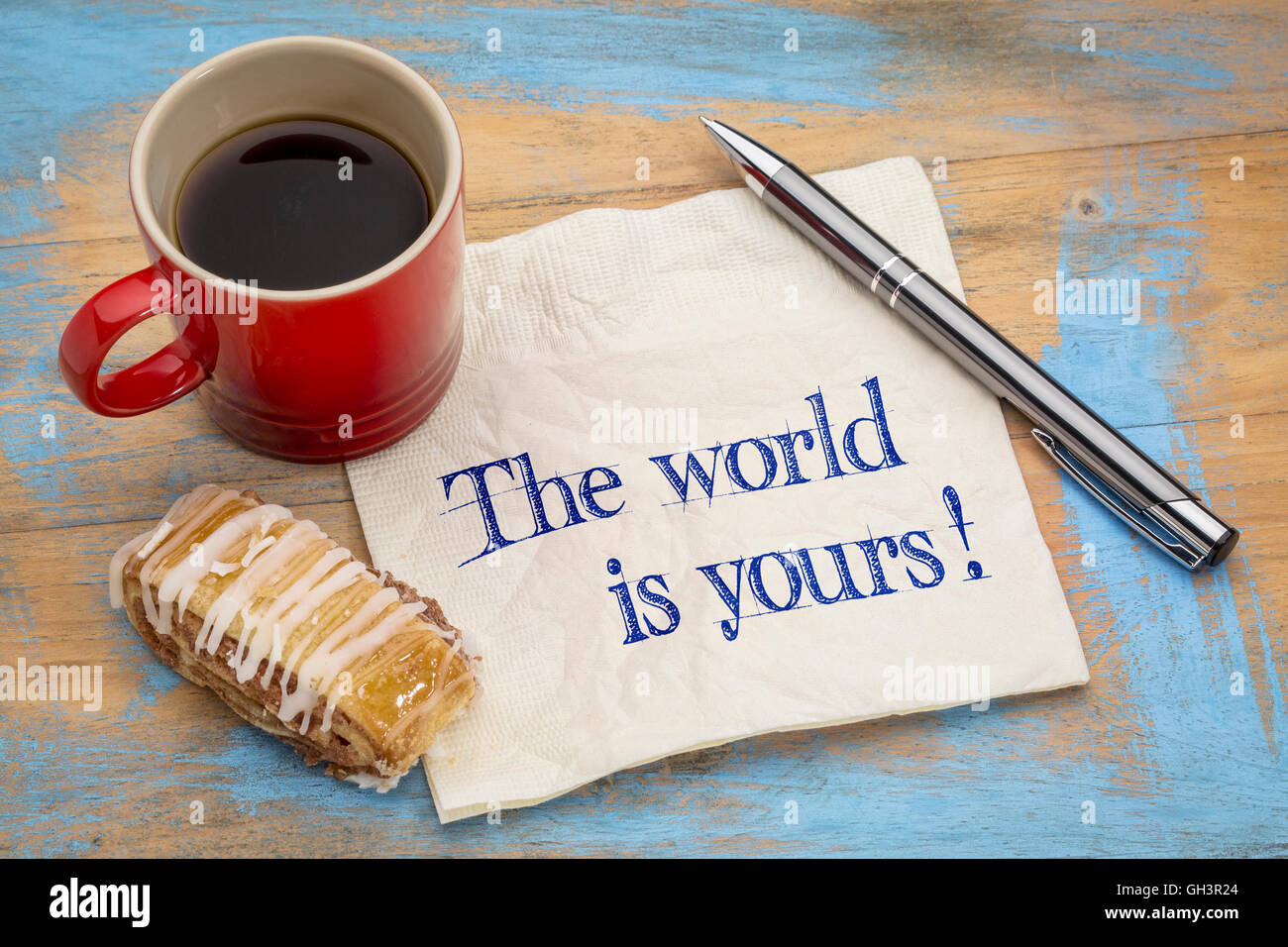Die Welt gehört Ihnen - eine positive Affirmation. Handschrift auf einer Serviette mit einem Kugelschreiber, Tasse Espresso und Cookie gegen grung Stockfoto