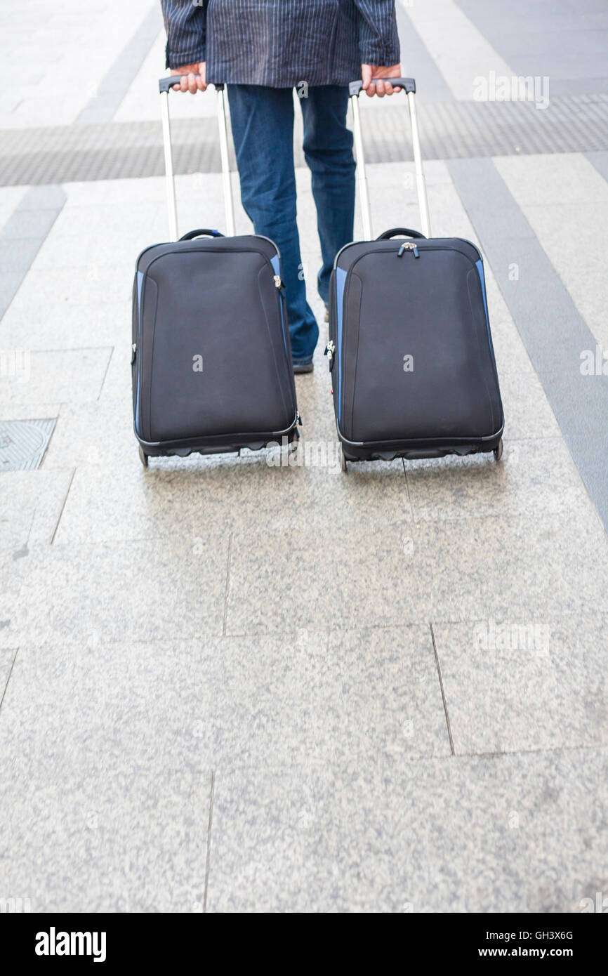Geringe Aussicht auf Reisen junger Mann zu Fuß mit zwei Koffern Stockfoto
