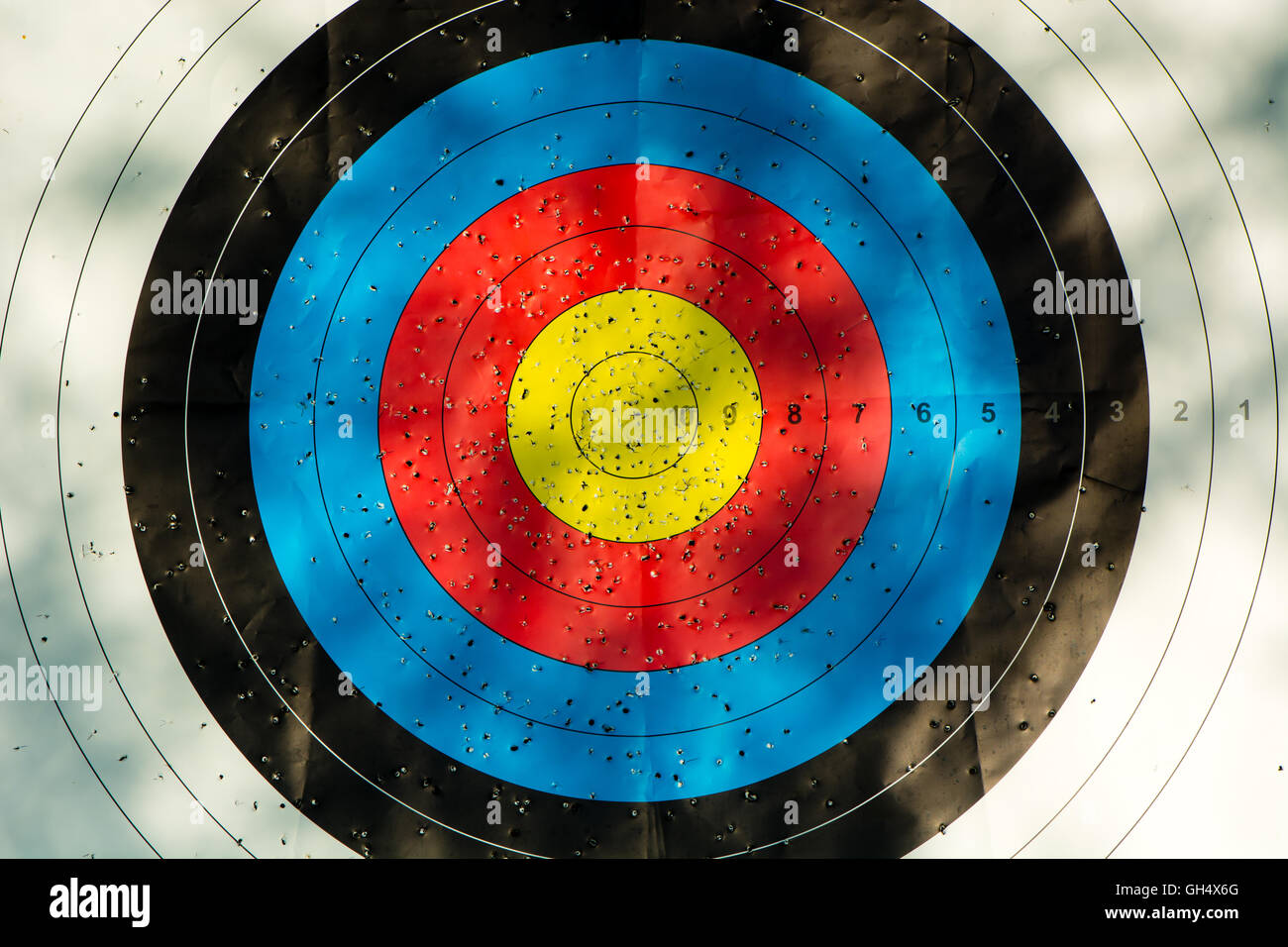 Zielscheibe mit Pfeil Löcher. Gold, rot, blau und schwarz Wettbewerb Ziel markiert wo Pfeile eingedrungen sind Stockfoto