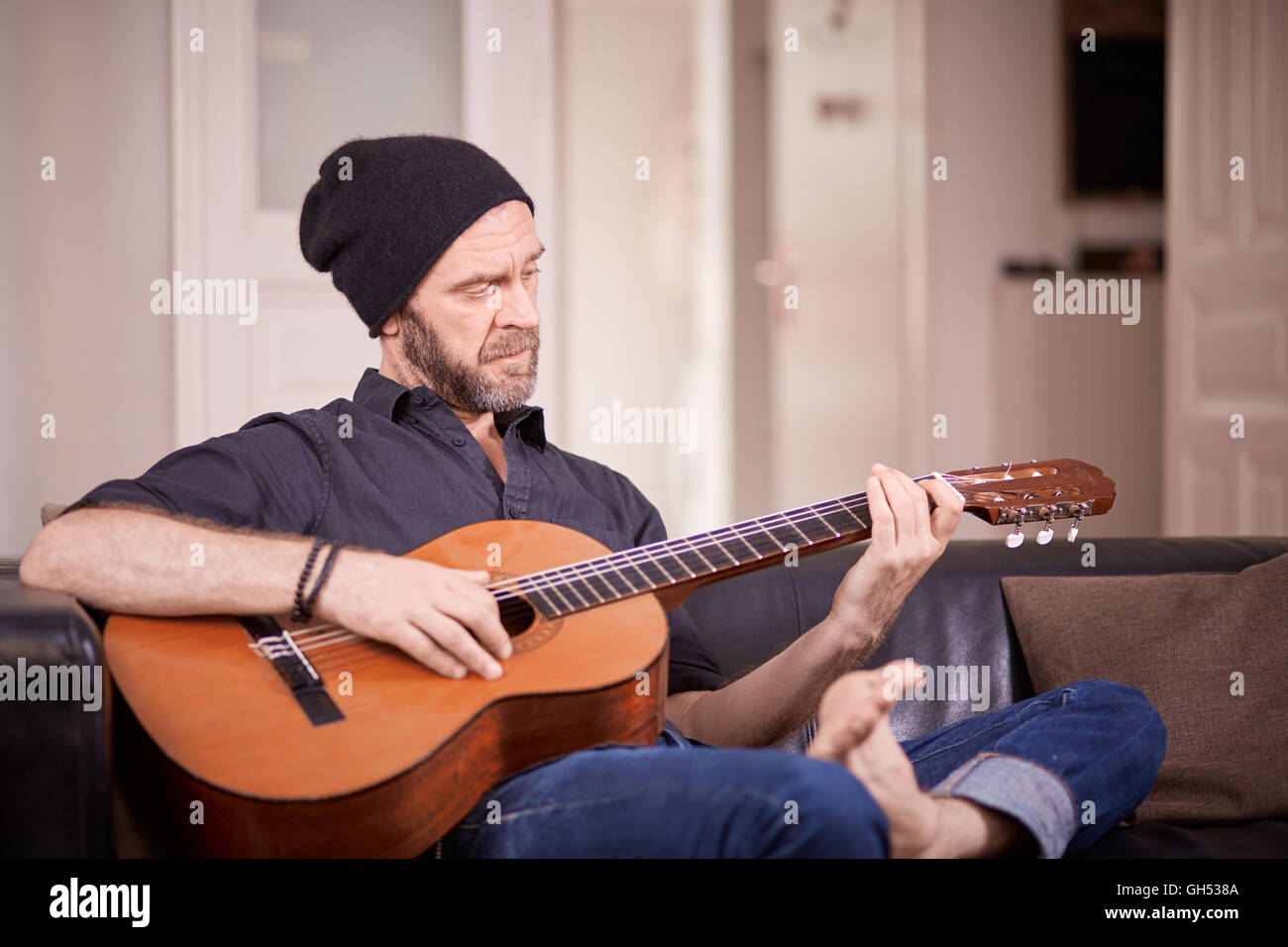 Coole alte Mann mit Bart, die Gitarre zu Hause auf der couch Stockfoto