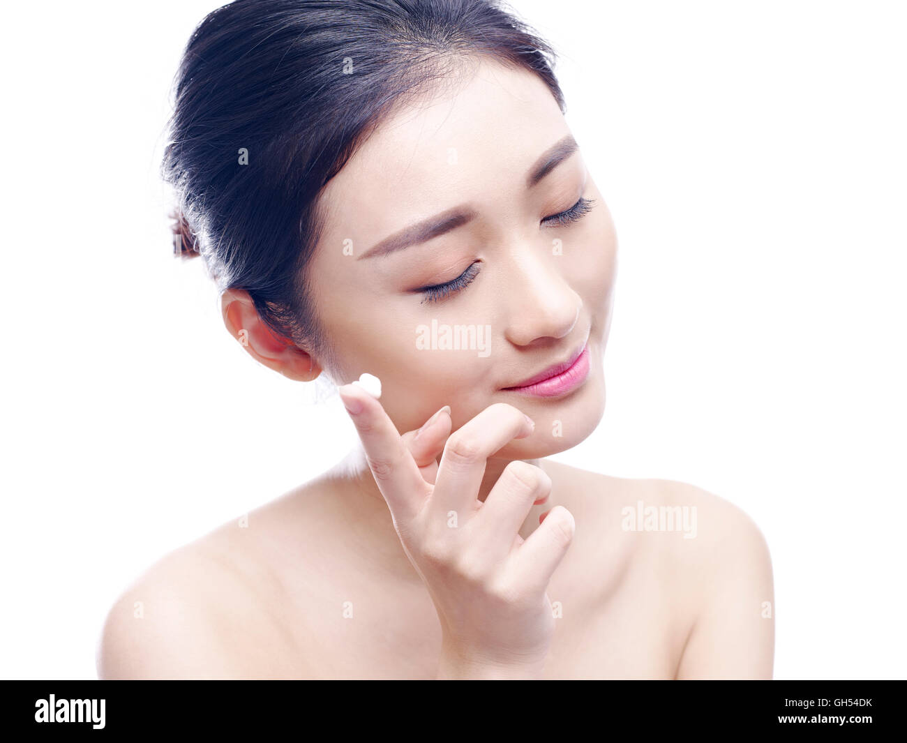 junge asiatische Frau Auftragen von Lotion oder Creme, Gesicht, isoliert auf weißem Hintergrund. Stockfoto