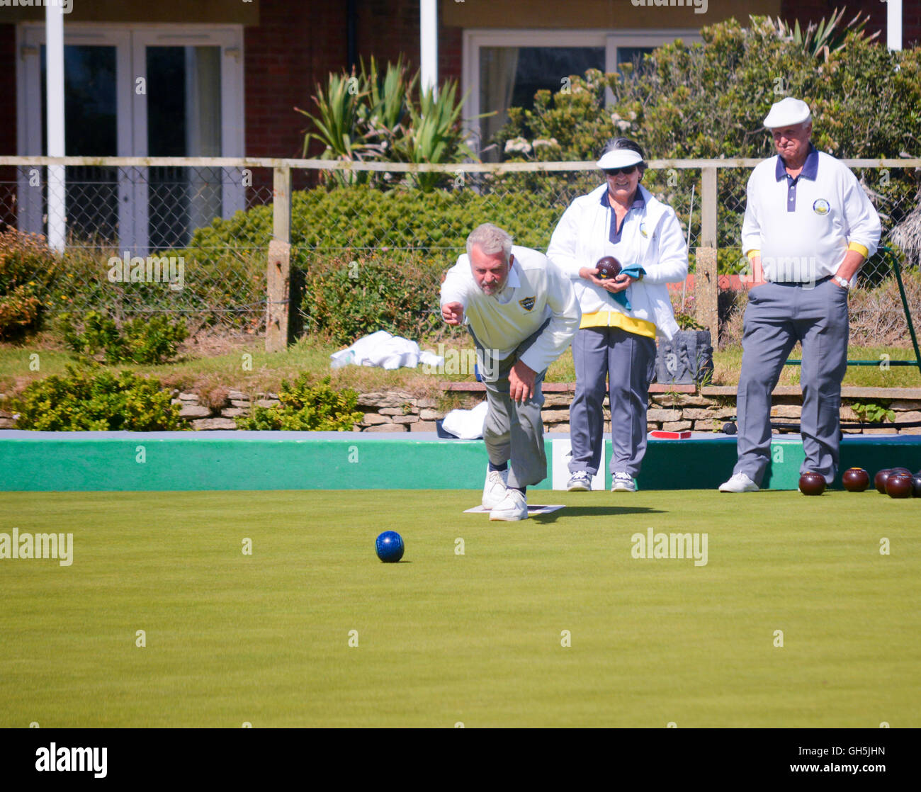 Senioren spielen einen Wettbewerb passen auf eine perfekte Bowling Green bei strahlendem Sonnenschein. Stockfoto