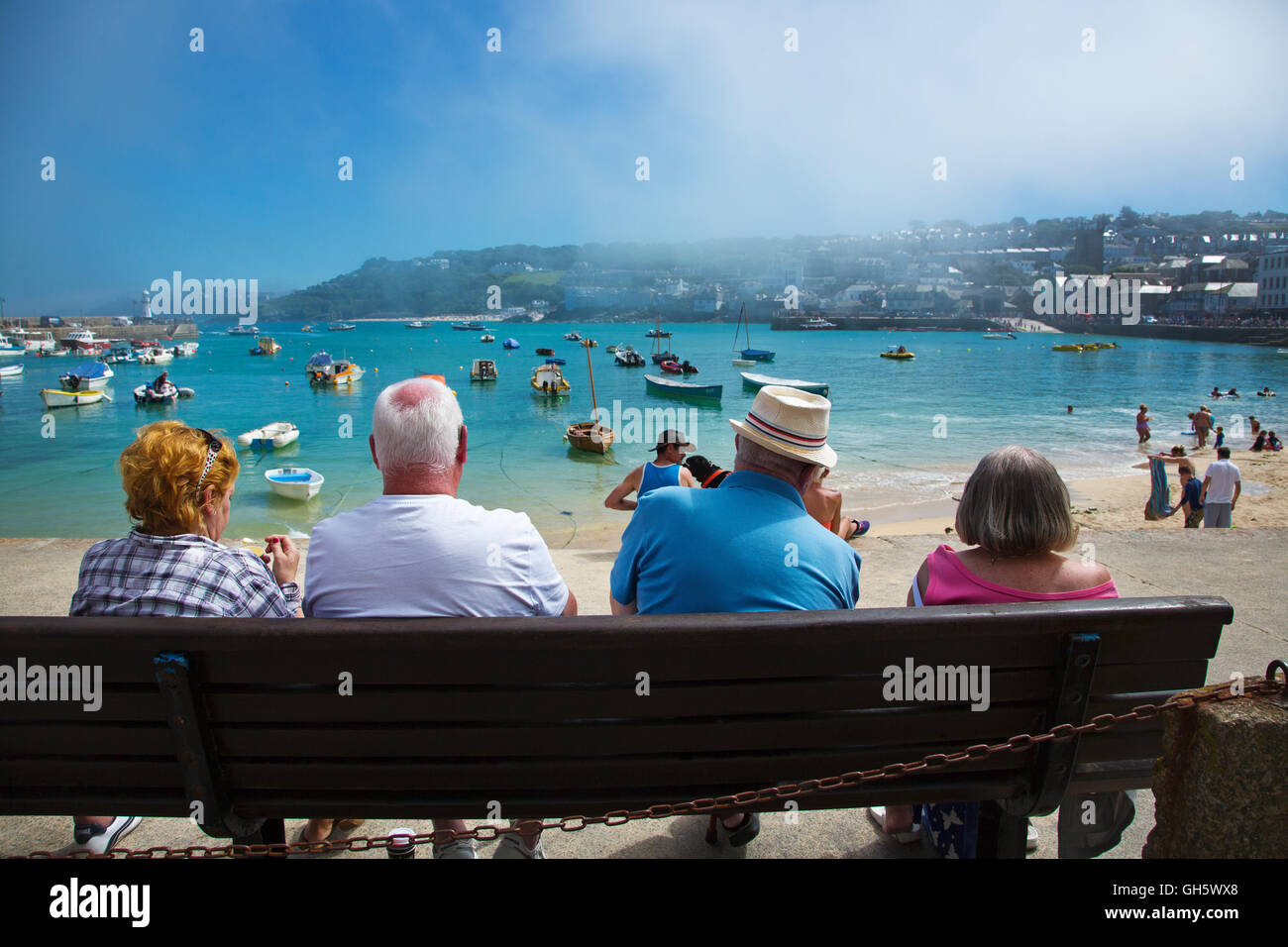 Touristen sitzen auf einer Bank, St. Ives, Cornwall, UK Stockfoto