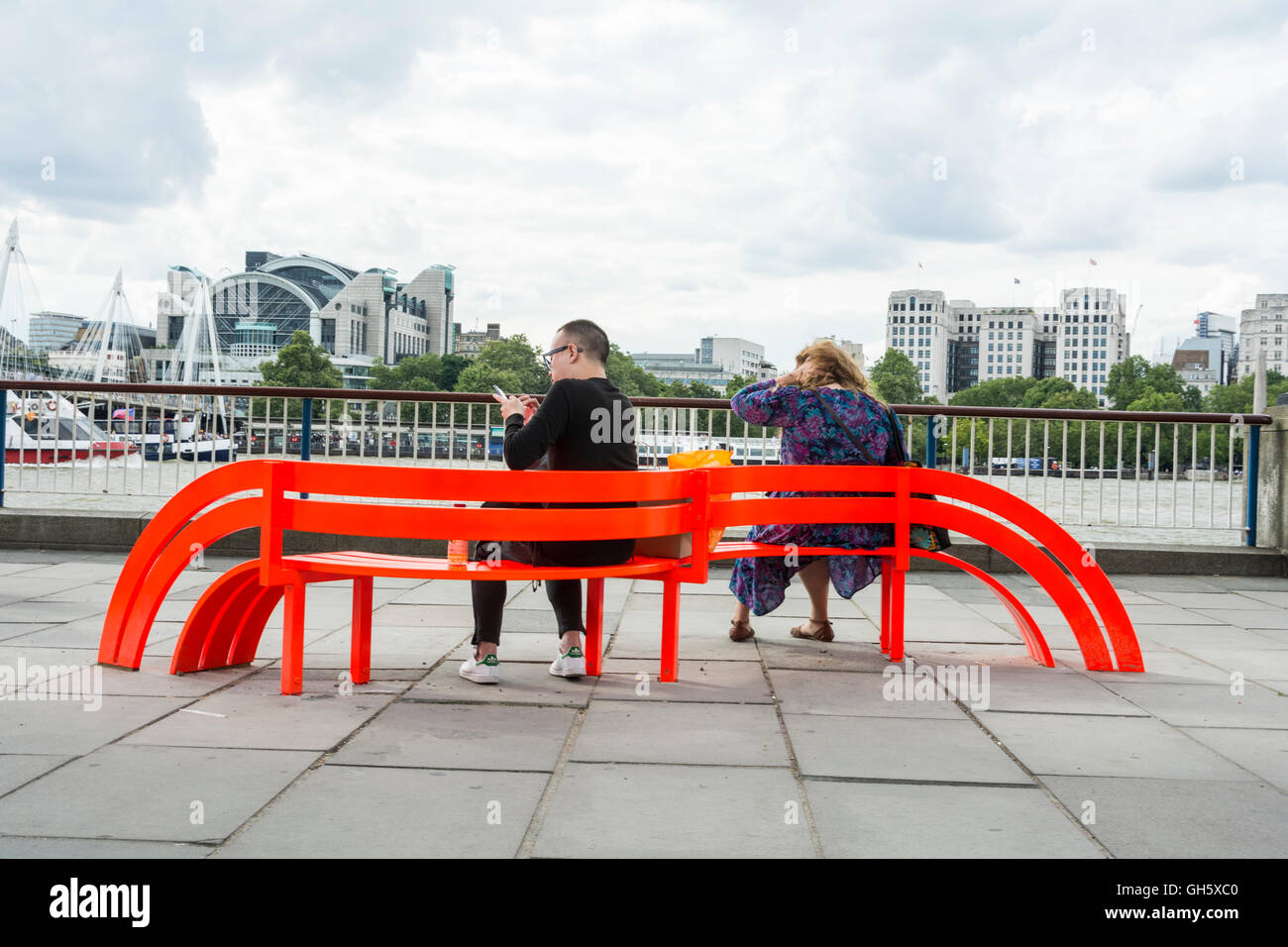 Ein paar sitzt auf einer von Jeppe Hein's veränderte soziale Bänke auf der Londoner South Bank, SE 1, Großbritannien Stockfoto