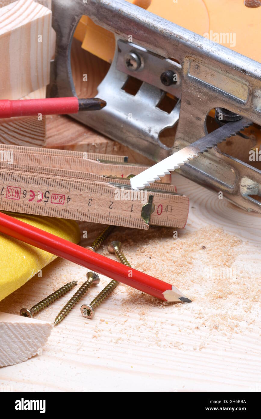 Nahaufnahme von Zimmerhandwerk-Werkzeuge und elektrische Stichsäge auf Holzbrett Stockfoto