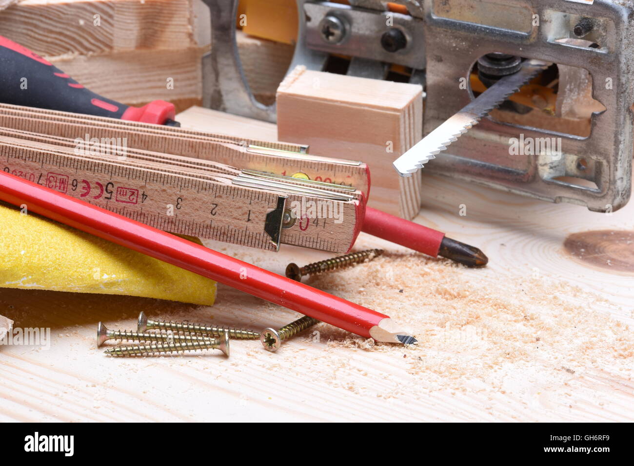 Nahaufnahme von Zimmerhandwerk-Werkzeuge und elektrische Stichsäge auf Holzbrett Stockfoto