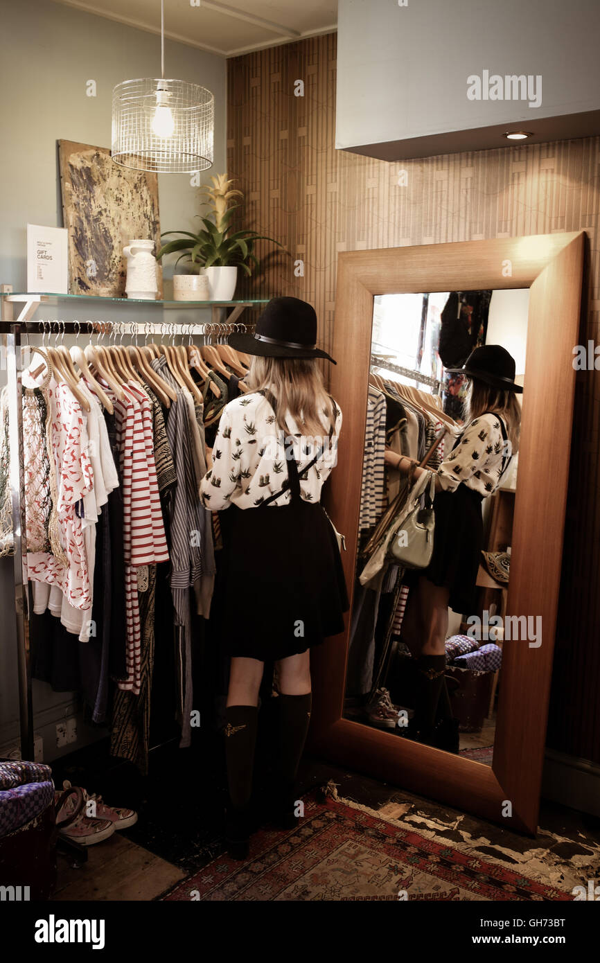 ein 12 Jahres altes Mädchen trägt einen schwarzen Hut in einem Vintage-Kleidung zu speichern, durchsuchen die Kleidung und stand neben einem Spiegel Stockfoto