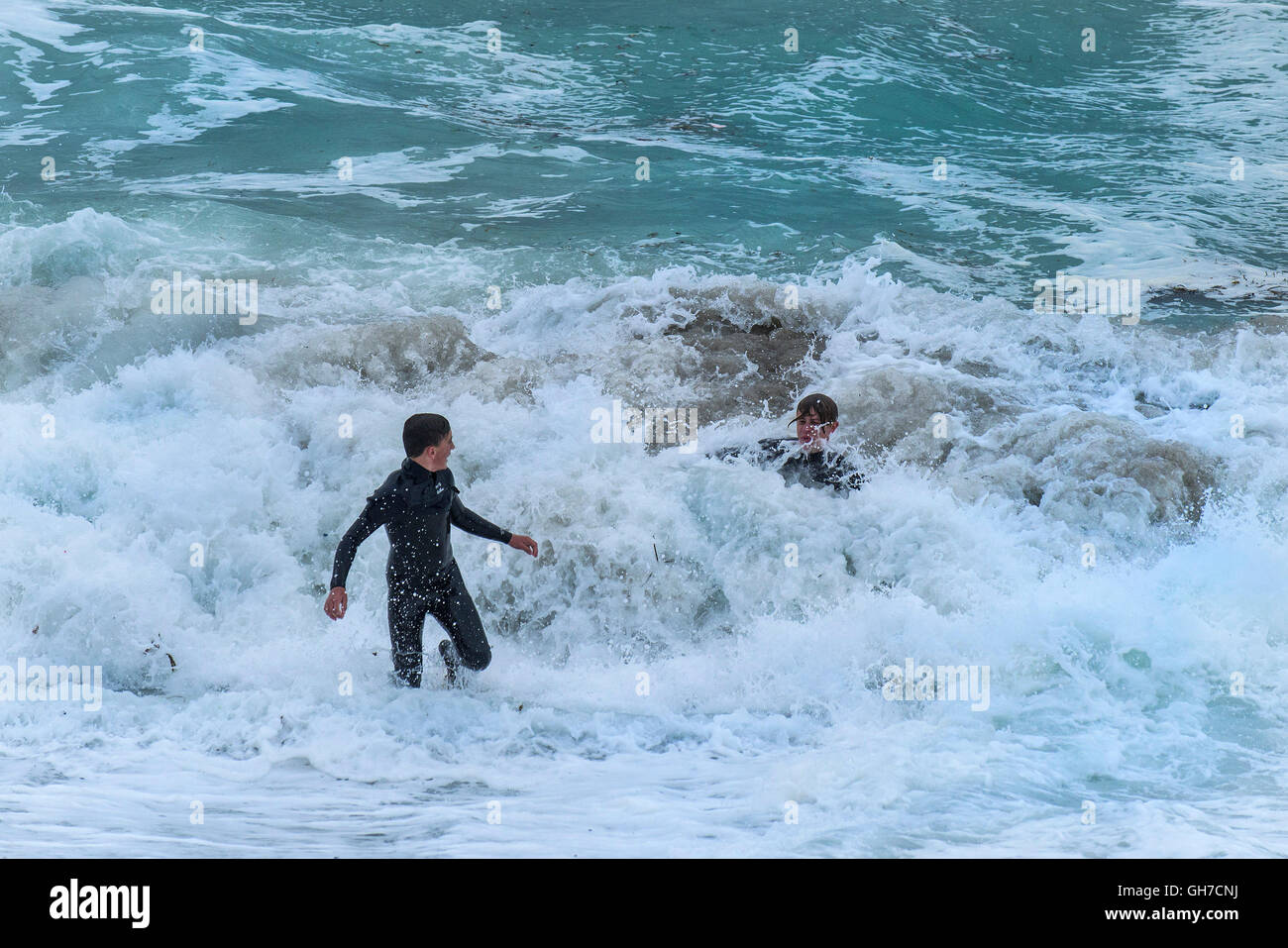 Zwei Jugendliche spielen in sehr rauen Wellen. Stockfoto