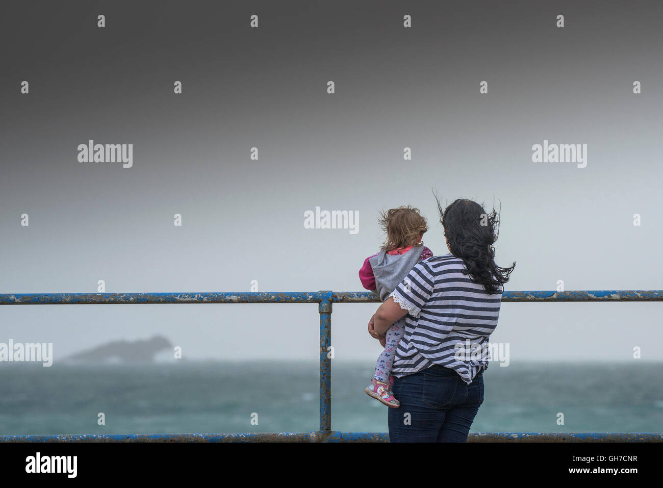 Eine Mutter und Kind aus Blick auf das Meer an einem windigen Tag in Newquay. Stockfoto
