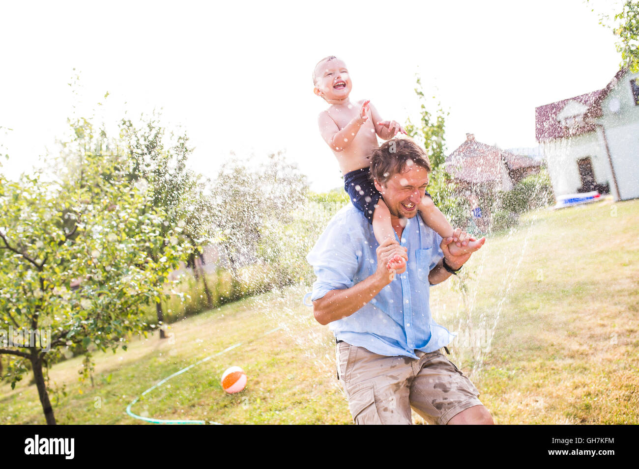 Kleiner Junge mit seinem Vater bei der Sprinkler, Sommer Stockfoto