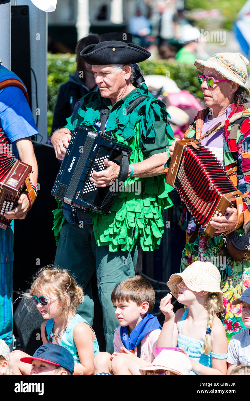 Broadstairs folk Week-Festival. Zwei Morris Männer Musiker spielen Akkordeon im Freien bei strahlendem Sonnenschein. Ein in Packwork mehrfarbige Jacke, bedeckt im Kostüm kurz grüne Luftschlangen. Kleine Kinder sitzen im vorderen genießen. Stockfoto