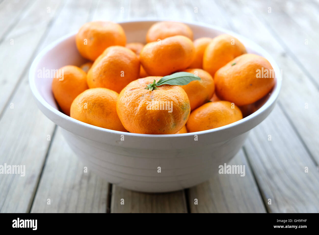 Unvollkommene Satsuma Mandarine - Bio-Obst produzieren - in einer weißen Schüssel auf einem hölzernen Hintergrund. Stockfoto