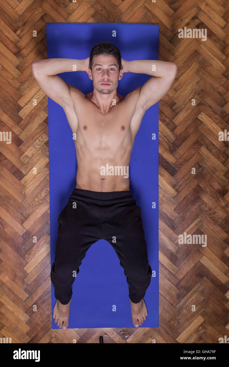Passform schlanke abs schönen Jüngling blickte erhöhten Blick über hohe entspannen. Verlegung der Matte Stockfoto