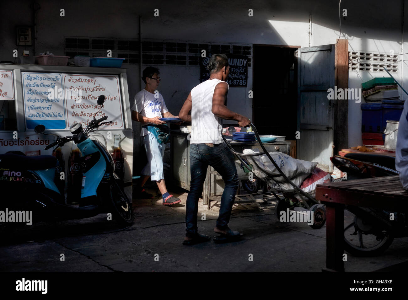 Gasse auf der Rückseite mit Männern, die im Schatten arbeiten. Thailand S. E. Asien Stockfoto