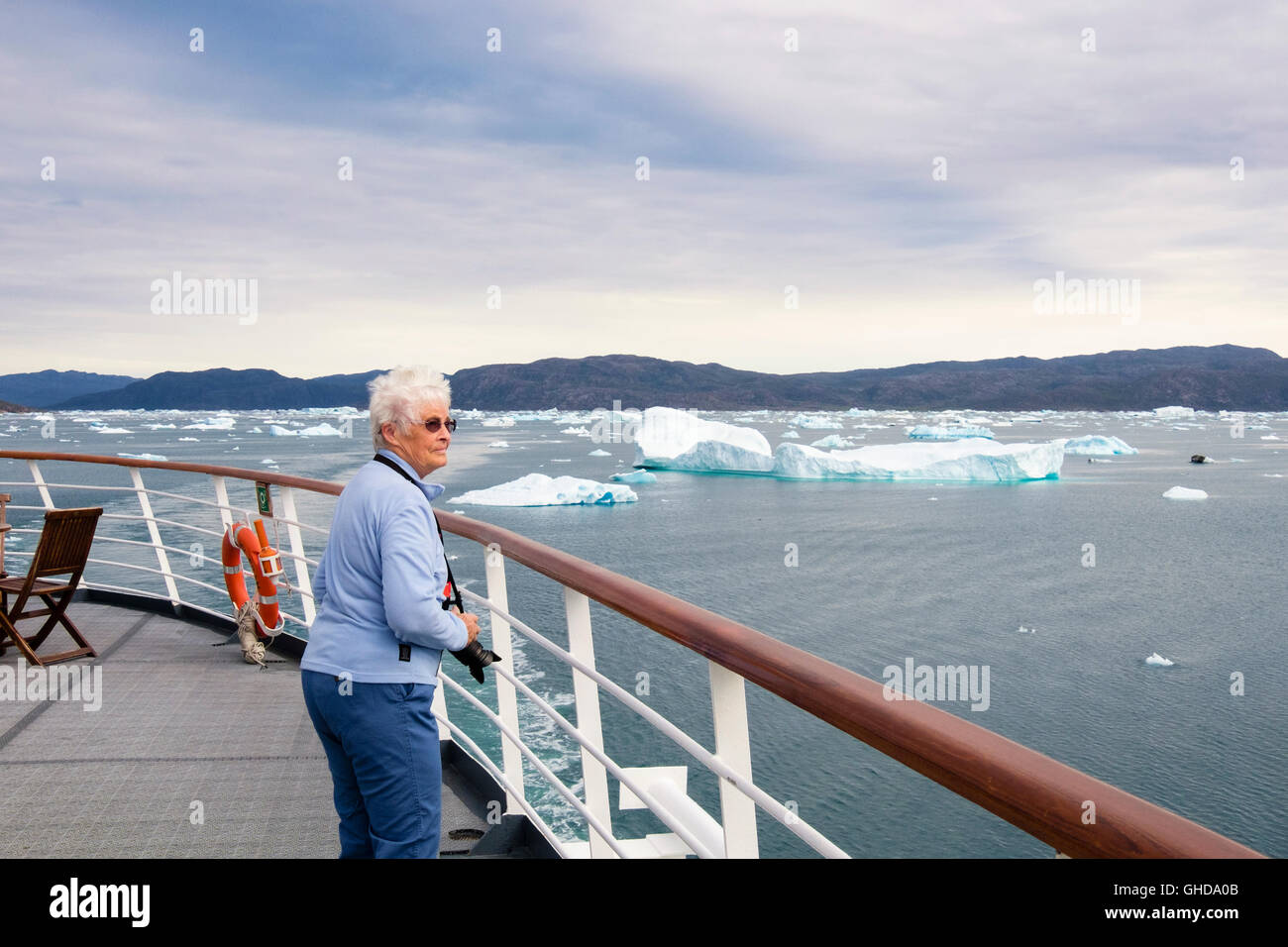 Pensionierte ältere weibliche touristische Passagier auf außerhalb Deck eines Kreuzfahrtschiffes segeln in Bredefjord Fjord mit Eisbergen im Sommer. Narsaq Grönland Stockfoto