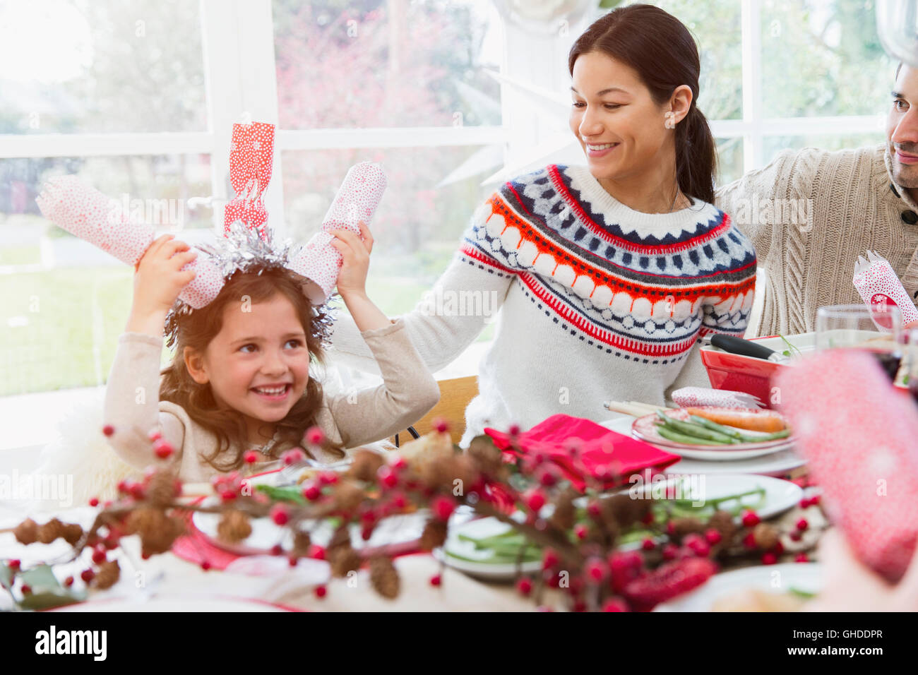 Verspielte Mädchen Kopf am Tisch Christmas Cracker festhalten Stockfoto