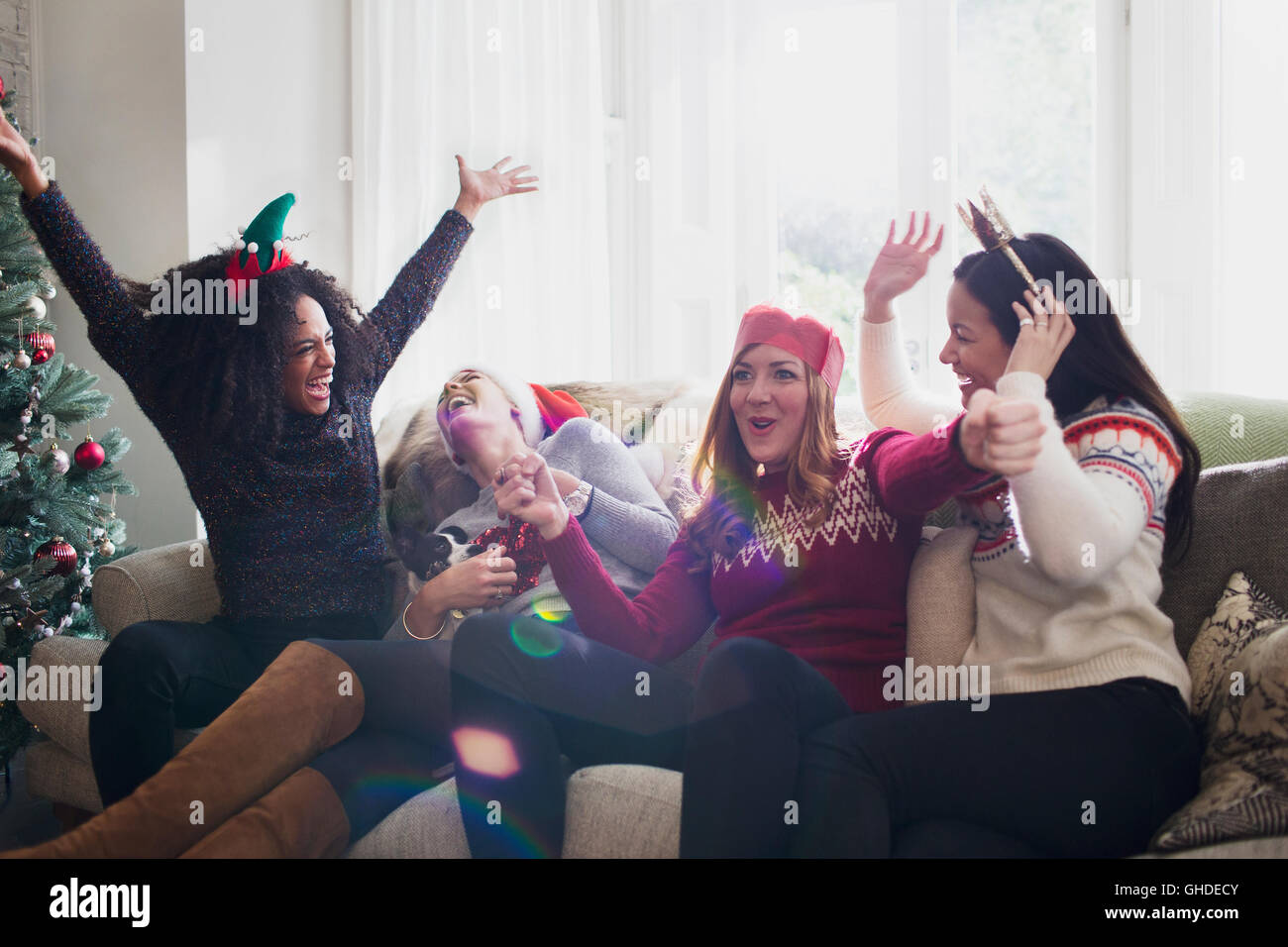 Lachenden Freunden Weihnachten zu feiern, auf sofa Stockfoto