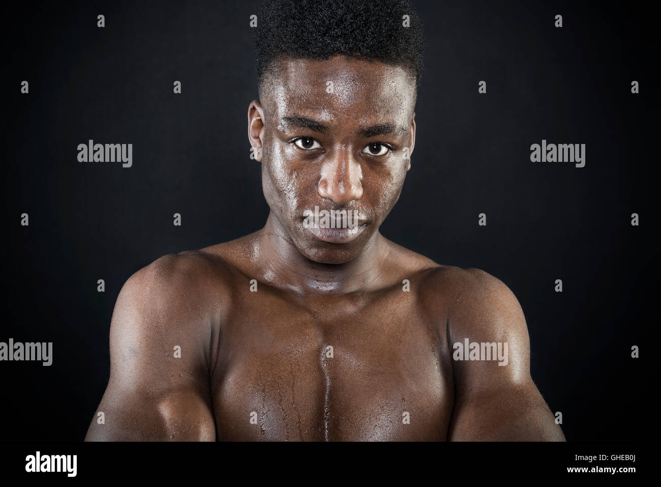 Sportler Sportler Schwitzen nass Gesicht Porträt nach Übung Arme intensiv gefaltet aussehen isoliert schwarz Stockfoto