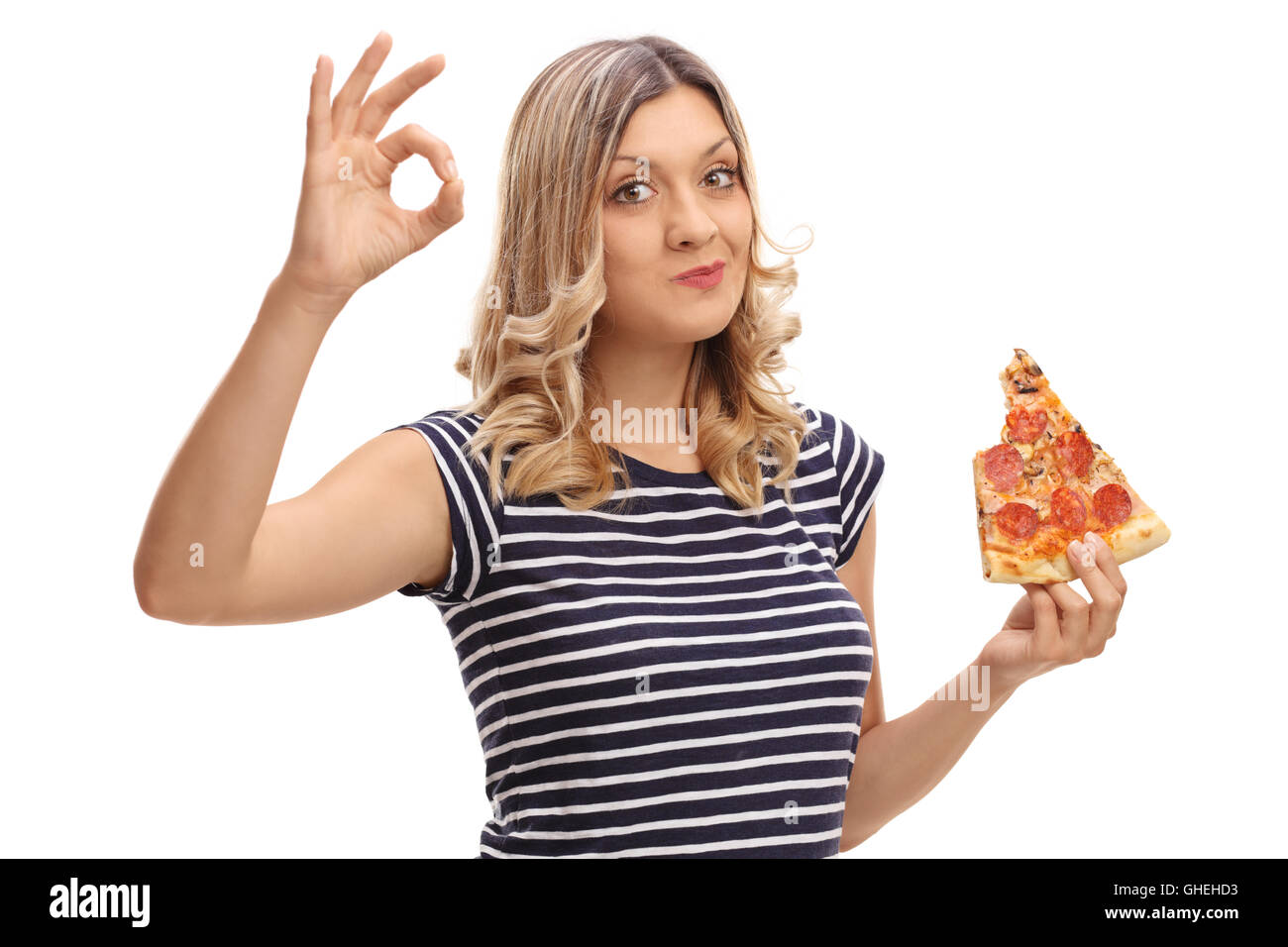 Junge, blonde Frau Essen ein Stück Pizza und macht eine Ordnung Geste mit der Hand isoliert auf weißem Hintergrund Stockfoto