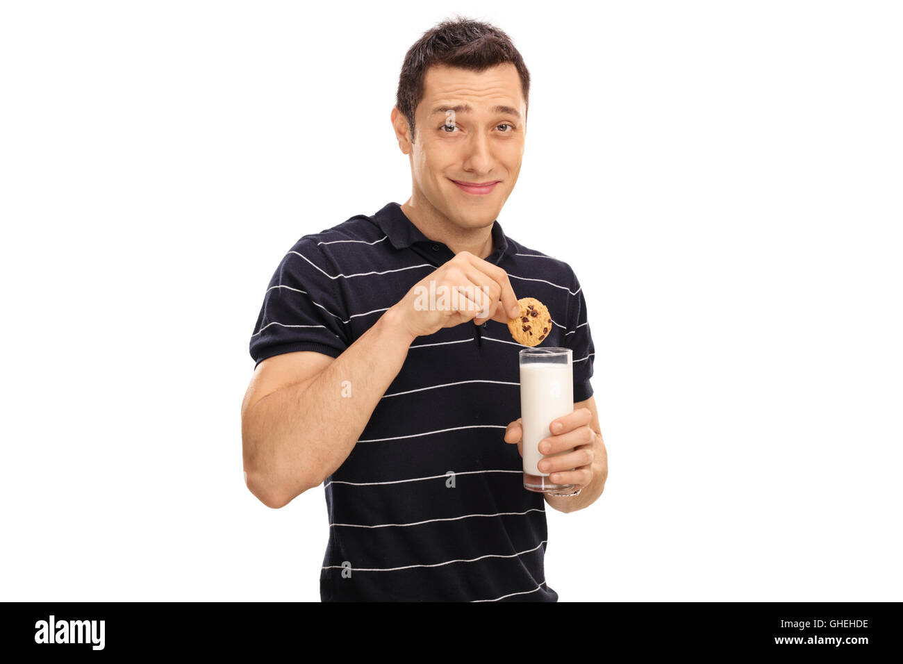 Junger Mann tauchen einen Cookie in ein Glas Milch isoliert auf weißem Hintergrund Stockfoto