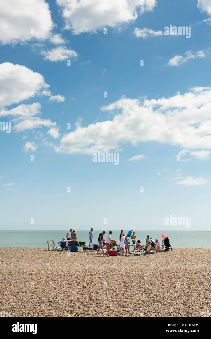 Eine Familie und große Gruppe von Menschen versammeln sich auf dem Kiesstrand in Aldeburgh Suffolk UK im Sommer an einem sonnigen Tag Stockfoto