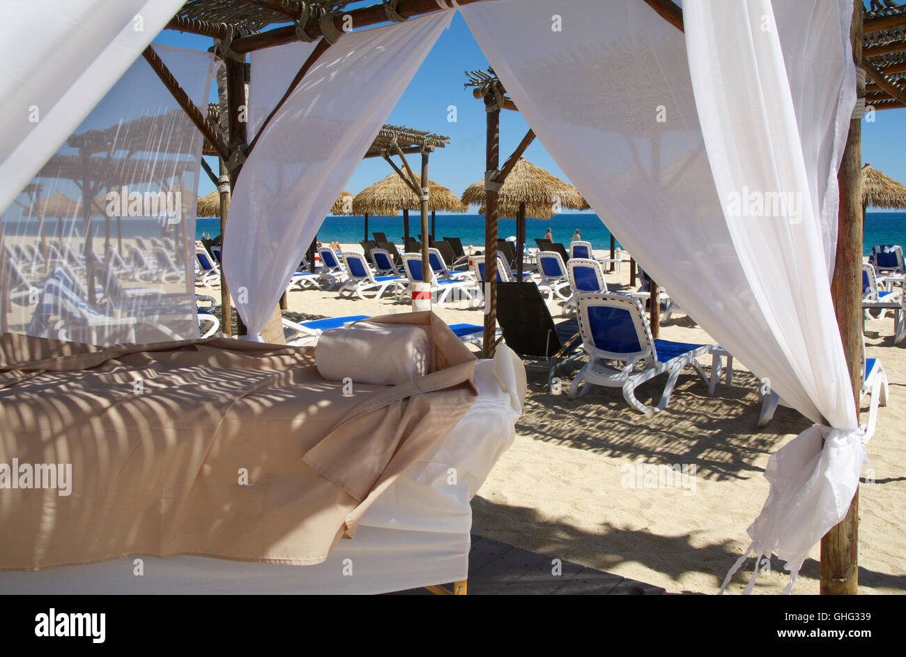 Outdoor-Massageliegen am White Sand Beach in einem Maya-Riviera Beachresort mit Blick auf das blaue Meer, Strand, Möbel und Hütten Stockfoto