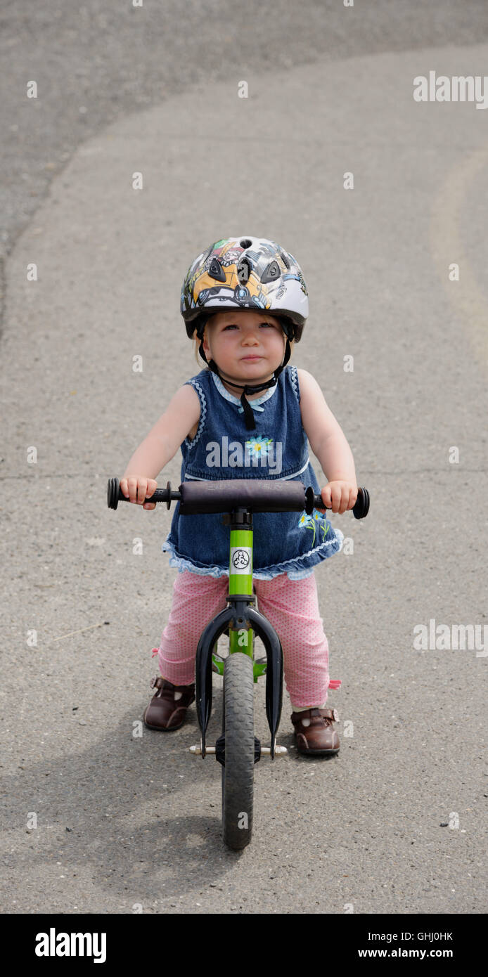 Ein kleines Mädchen (2 Jahre alt) auf einem Laufrad Stockfoto