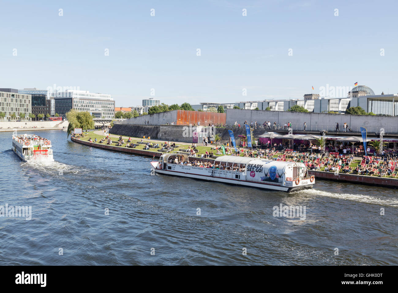 Ausflugsboote auf der Spree mit Menschen entspannen Sie sich auf Liegestühlen im Capital Beach Bar, Berlin, Deutschland Stockfoto
