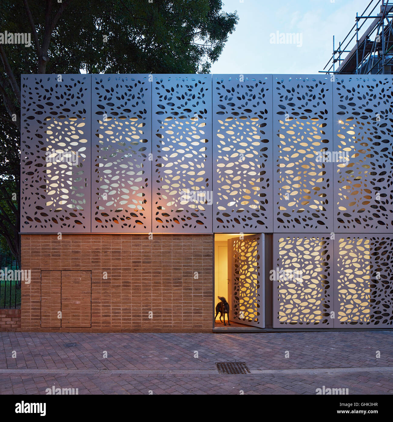 Vorderansicht der Eingangsfassade mit Metallschirm in der Abenddämmerung. Haus in Brixton, London, Vereinigtes Königreich. Architekt: Horden Cherry Lee Architects Ltd, 2016. Stockfoto