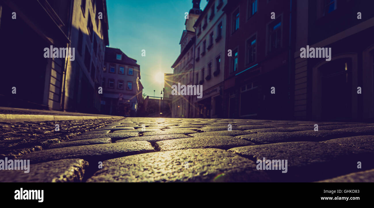 Sonnenaufgang in der Stadt auf der Straße mit Pflastersteinen Stockfoto