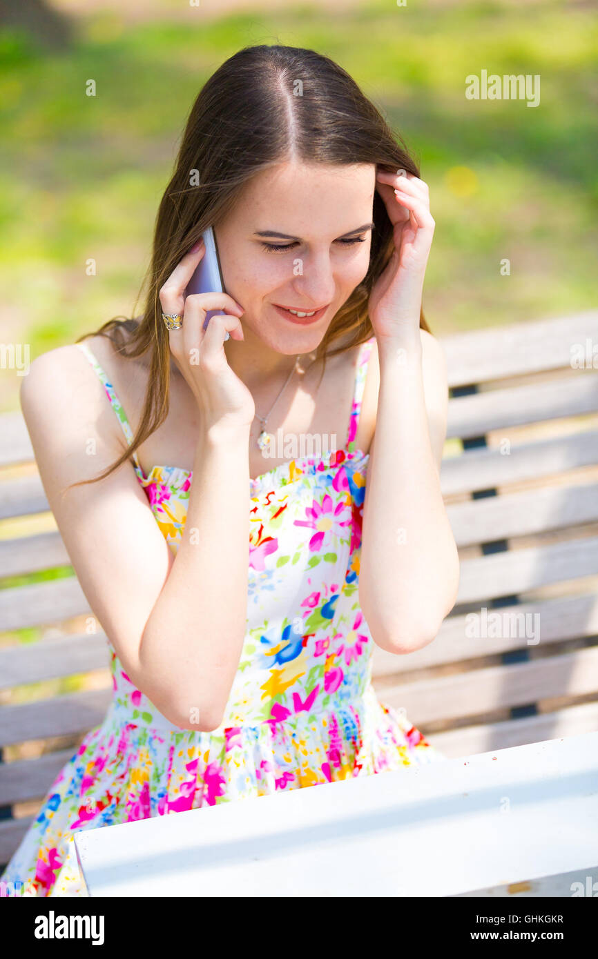 Junge Frau Nutzung Handy im Frühlingspark Stockfoto